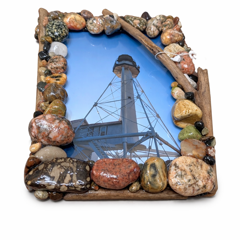 Decorative frame made of natural stones with a lighthouse image inside on a white background